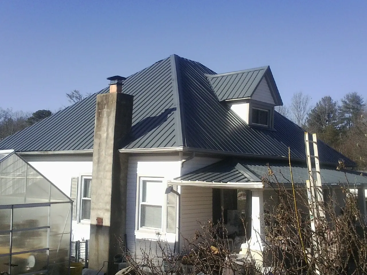 Dark blue standing seam metal roof on a white farmhouse with dormer — Slate & Tile Roof Repair by Roofing Brothers in Millersport