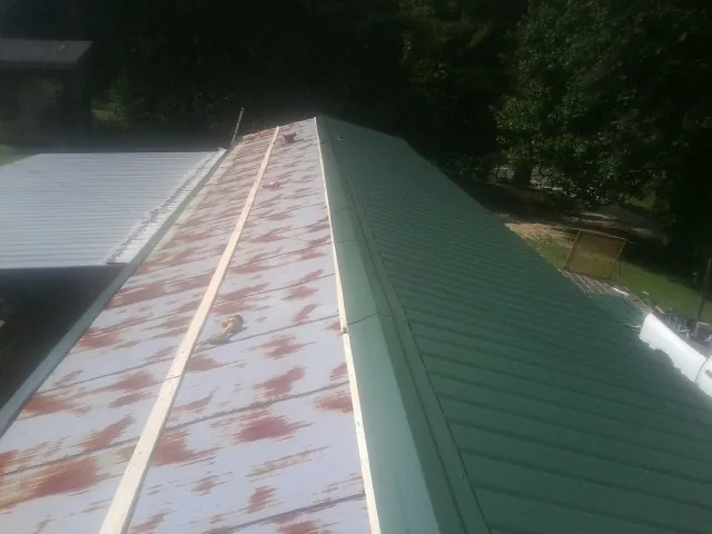 Old rusted panels beside newly installed green metal roofing — Wind Damage Roof Repair by Roofing Brothers in Millersport