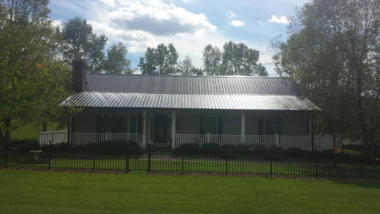 Gray metal roof on a brick ranch with a full width front porch — Gutter Guard Installation work by our crew in Millersport
