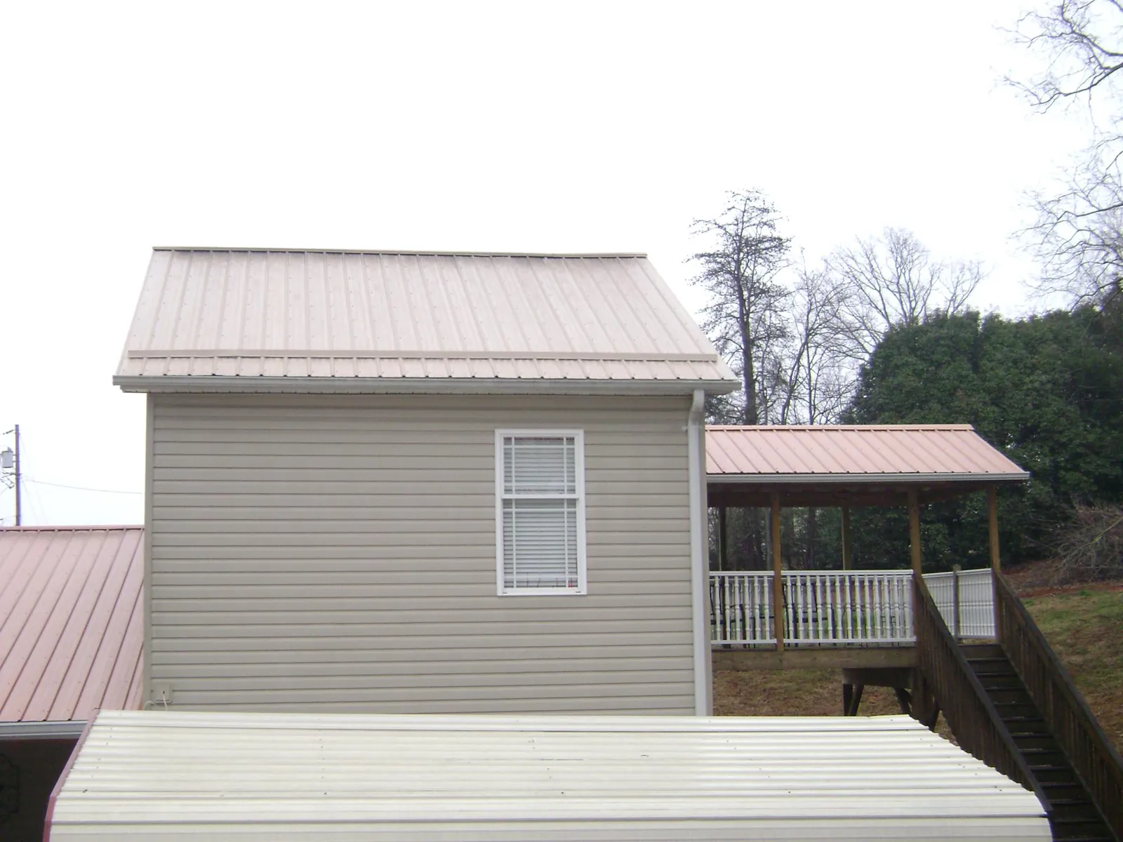 Tan metal roofs on a two story addition and attached porch, from a Roof Replacement job in Millersport