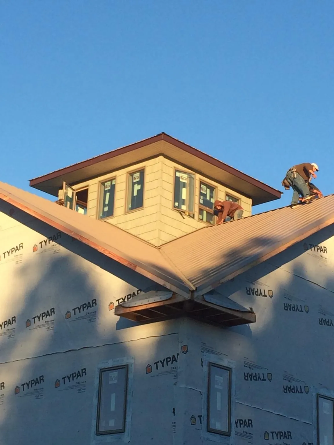 Roofers working around a rooftop cupola on a new metal roof at sunset — Roof Waterproofing in Millersport by Roofing Brothers